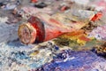 Closeup of old oil paint tube with red colour lying on palette Royalty Free Stock Photo