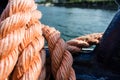 Closeup of an old red frayed boat rope, water background with landscape Royalty Free Stock Photo