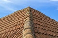 Old ridge roof tiled with dirty wave-shaped clay tiles against blue sky. Photo in perspective with selective focus Royalty Free Stock Photo