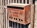 Closeup of an old rusty mailbox on a wooden gate