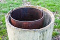 Closeup of an old rusty metallic barrel in a garden surrounded by greenery under sunlight