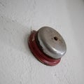 Closeup of an old rusty school bell on a white wall under the lights