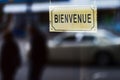 closeup of an old signboard with the text bienvenue, open welcome written in french, on the street in front of a store Royalty Free Stock Photo