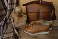 closeup old things, stack of vintage books, globe, shoes, leather military satchel on table, checkered grandmother\'s plaid,