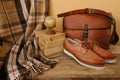 closeup old things, stack of vintage books, globe, shoes, leather military satchel on table, checkered grandmother\'s plaid,