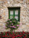 Closeup of an old vintage green window on a stone rustic cozy mountain village house with colorful flowers and brick stone facade Royalty Free Stock Photo