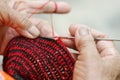 Closeup old woman in countryside, Thailand knitting by knitting needle and red and black yarn doing handmade bags at her home