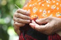 Closeup old woman in countryside, Thailand knitting by knitting needle and red and black yarn doing handmade bags at her home Royalty Free Stock Photo