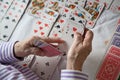 Closeup of wrinkled hands of senior lady playing solitaire