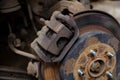 Closeup old, worn out and rusty car brake system. Rear disc brake of a car with a removed wheel.