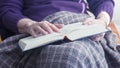 Closeup of older woman sitting by window and reading a book Royalty Free Stock Photo