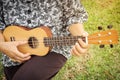 Closeup oldwoman playing ukulele. Sitting on grass. Royalty Free Stock Photo