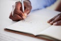 Closeup of one african american businessman writing notes in a book while working in at a desk in an office. Hands of Royalty Free Stock Photo