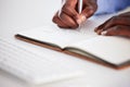 Closeup of one african american businessman writing notes in a book while working in at a desk in an office. Hands of Royalty Free Stock Photo