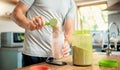 Closeup of one caucasian man pouring a scoop of chocolate whey protein powder to a health shake for energy for training