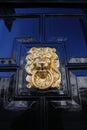 Closeup of one isolated antique old lion head face door knocker with ring at shiny polished black wood door