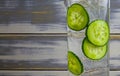 Closeup of one isolated cocktail glass with gin tonic raw cucumber slices and ice cubes. wooden old white vintage planks Royalty Free Stock Photo