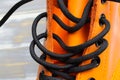 Closeup of one single bright orange color leather boot with black sole and laces, yellow stitching on white wood background Royalty Free Stock Photo