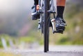 Closeup of one woman cycling outside. Sporty fit female athlete with her feet on bicycle pedals while riding a bike on a Royalty Free Stock Photo