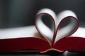 Closeup of an open book, novel with pages bent, shaped into a heart pattern to show the concept of a love to read Royalty Free Stock Photo