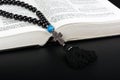 Closeup of opened Holy Bible and rosary beads with cross on black background. Religion concept. Cyrillic text Royalty Free Stock Photo