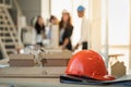 Closeup of orange hard safety helmet hat of workman as engineer on black folder with house model and engineering and architect Royalty Free Stock Photo