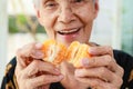 Closeup of organic fruit,old elderly holding juicy orange in hands,senior woman showing peeled tangerine,vitamin C from orange Royalty Free Stock Photo