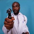 Closeup of otoscope in hand of african american doctor with funny face expression