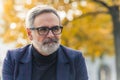 Closeup outdoor portrait of caucasian man in his 60s with gray hair and gray beard, wearing glasses with black frame Royalty Free Stock Photo