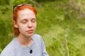 Closeup outdoor portrait of a young beautiful redhead woman smiling dreamy with her eyes closed, grass background Royalty Free Stock Photo