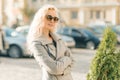 Closeup outdoor portrait of young smiling blond woman with sunglasses with long curly hair. On city street sunny day Royalty Free Stock Photo