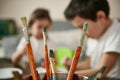 Closeup of paint brushes on the background of blurred children concentrate on decorating eggs for Easter Royalty Free Stock Photo