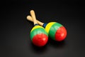 A pair of colorful maracas lying on a black underground