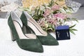 Closeup of a pair of elegant green high heels with beautiful earrings for the wedding