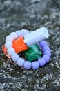 closeup the pair of green ,orange white color nail paint glass bottle with white purple bracelet soft focus natural grey brown Royalty Free Stock Photo