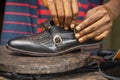 Closeup of a pair of hands fixing a black shoe on a wooden surface