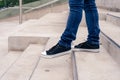 Closeup of a pair of man`s legs in black sneakers going down concrete stairs. modern urban concept Royalty Free Stock Photo
