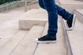 Closeup of a pair of man`s legs in black sneakers going down concrete stairs. modern urban concept Royalty Free Stock Photo