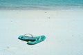 Closeup pair of old sandals put on the white sand beach with blurred sea surfing into the coast background Royalty Free Stock Photo