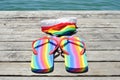 Rainbow-patterned flip-flops and swimsuit on dock Royalty Free Stock Photo