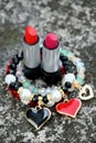closeup the pair of red,pink color lipstick silver black tube with red white plastic beads bracelet soft focus natural grey brown Royalty Free Stock Photo