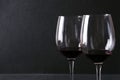 Closeup of pair of wine glasses with red wineagainst dark wall. Delicious best luxury wine