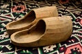 Closeup of a pair of wooden shoes on a beautiful carpet.