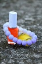 closeup the pair of yellow ,orange white color nail paint glass bottle with white purple bracelet soft focus natural grey brown Royalty Free Stock Photo