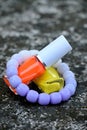 closeup the pair of yellow ,orange white color nail paint glass bottle with white purple bracelet soft focus natural grey brown Royalty Free Stock Photo