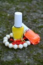 closeup the pair of yellow ,orange white color nail paint glass bottle with white red bracelet soft focus natural grey brown Royalty Free Stock Photo