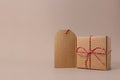 Closeup of parcels in brown wrapping paper and blank tags or labels copy space for text, isolated on beige background Royalty Free Stock Photo