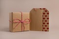 Closeup of parcels in brown wrapping paper and blank tags or labels copy space for text, isolated on beige background Royalty Free Stock Photo