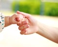 Closeup parent and baby holding hand together