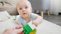 Closeup of parent giving plastic toy blocks to little baby boy playing on carpet. Concept of children development Royalty Free Stock Photo